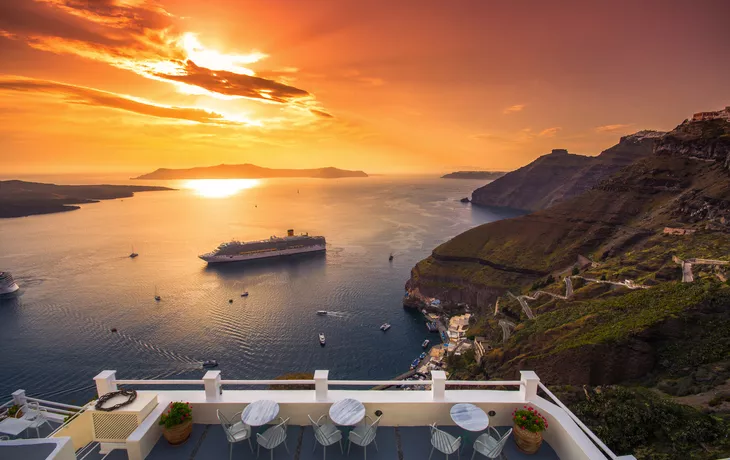 Abendansicht von Santorini mit Kreuzfahrtschiffen bei Sonnenuntergang