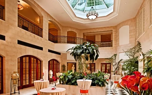 Wintergarten mit Tischdekorationen, großen Pflanzen und Glasdach.