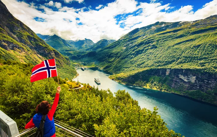 Tourist über Geirangerfjord mit norwegischer Flagge