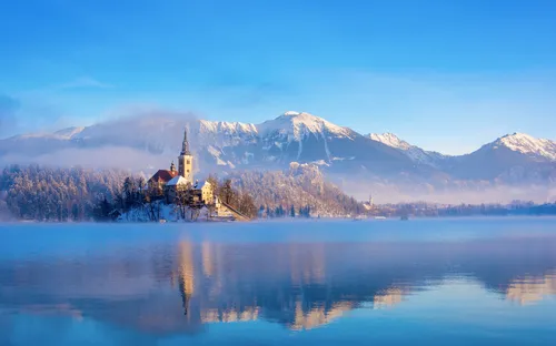 Bleder See an einem sonnigen Wintermorgen mit klarem Himmel und schneebedeckten Bergen