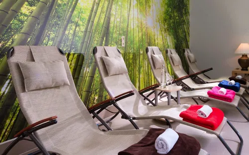 Ruheraum mit Liegestühlen, Pflanzen und bunten Handtüchern in einem Spa-ähnlichen Ambiente.