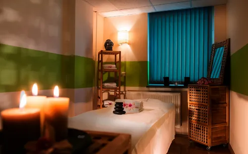 Entspannungsraum mit Massagebett, Kerzen und Regalen im AHORN Waldhotel Altenberg.