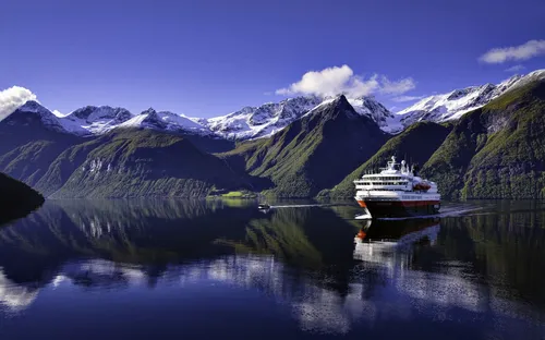 Kreuzfahrtschiff im Hjørundfjord in Norwegen vor schneebedeckten Bergen.