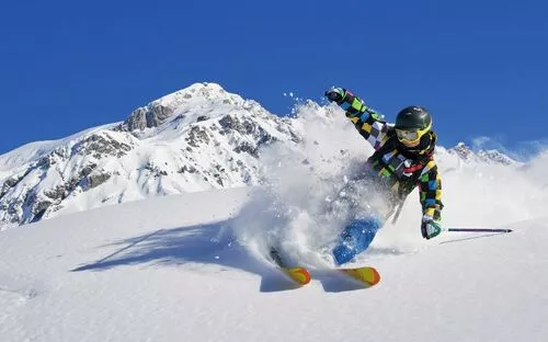 Person beim Skifahren im Tiefschnee vor schneebedecktem Bergpanorama