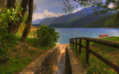 Bach und Bank mit Blick auf See und Berge im Hintergrund