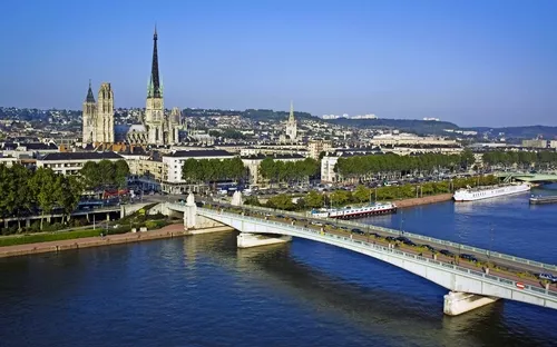 Stadtansicht mit Brücke über einen Fluss und historischer Architektur im Hintergrund.