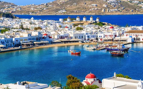 Mykonos mit Blick auf den Hafen, weiße Häuser und Windmühlen im Hintergrund.