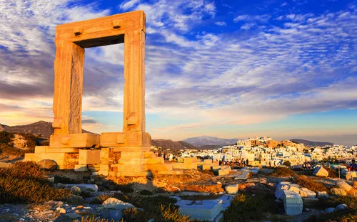 Antikes Tor mit Stadt im Hintergrund bei Sonnenuntergang.