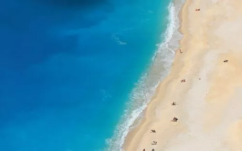 Strand mit blauem Wasser und Menschen von oben gesehen.