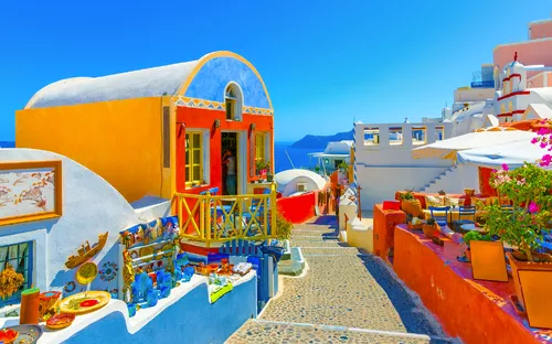 Malerische Straße mit weiß-blauen Gebäuden und bunten Details bei sonnigem Himmel.