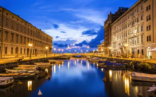 Kanal in einer Stadt bei Dämmerung, beleuchtet von Straßenlaternen.