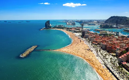 Strand von Barcelona mit Blick auf das Meer und Stadtgebäude im Hintergrund.