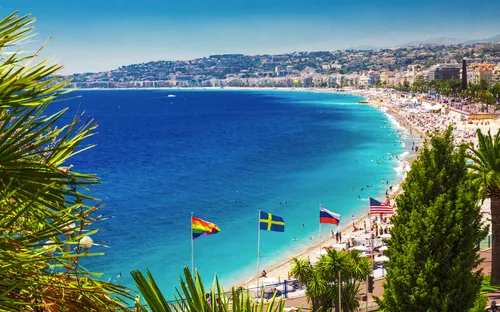 Blick auf eine Küstenstadt mit Strand, Palmen und blauem Meer.