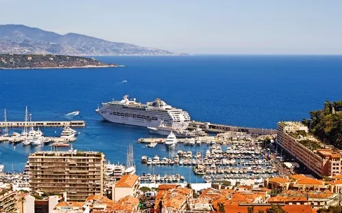 Kreuzfahrtschiff im Hafen von Monaco mit Blick auf das Mittelmeer und die umliegenden Hügel.