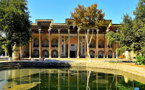 Historisches Gebäude mit Säulen und reflektierendem Teich im Vordergrund.