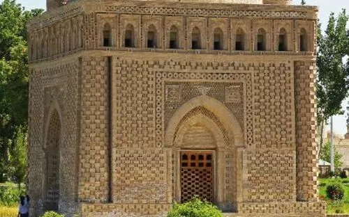 Historisches Mausoleum mit Kuppel und verzierten Ziegeln, umgeben von Garten.
