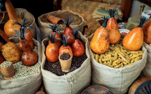 Verschiedene Gewürze und getrocknete Früchte in Jutesäcken auf einem Marktstand.