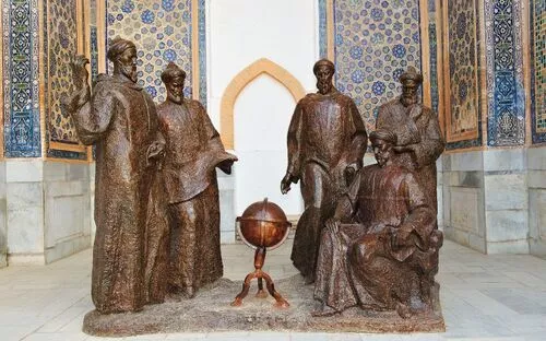 Bronzestatuen von sechs Personen und einem Globus in dekorativer Umgebung.