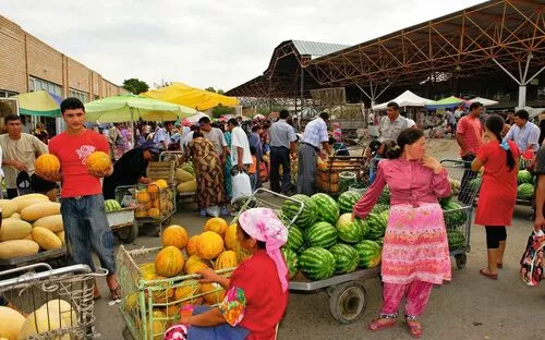Menschen kaufen und verkaufen Melonen auf einem belebten Marktplatz im Freien.