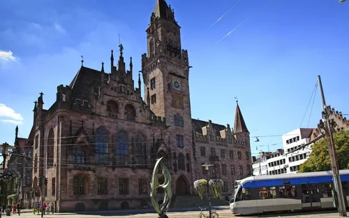 Historisches Gebäude mit Turm und Straßenbahn im Vordergrund.