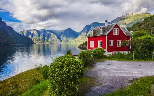 Rotes Haus am Faleidfjord in Olden, Norwegen, umgeben von beeindruckender Fjordlandschaft.