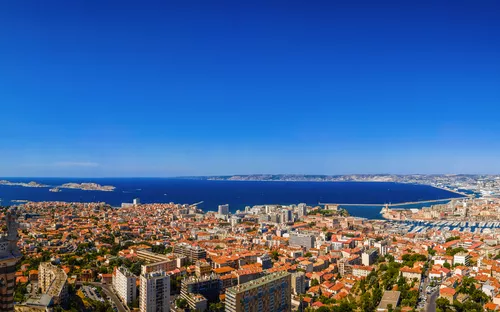 Blick über Marseille mit Notre-Dame de la Garde und Mittelmeer im Hintergrund.
