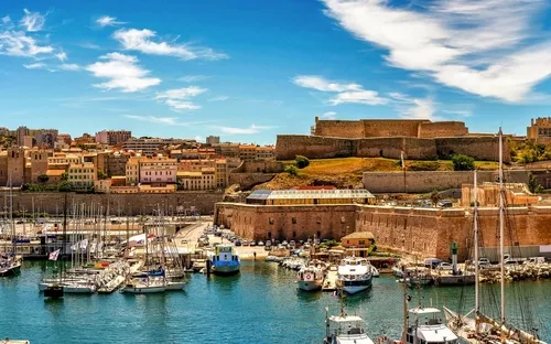 Hafenstadt mit Segelbooten und historischen Gebäuden bei sonnigem Wetter.