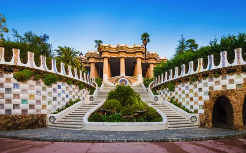 Monumentale Treppe im Park Güell, Barcelona, umgeben von Mosaiken und Pflanzen.