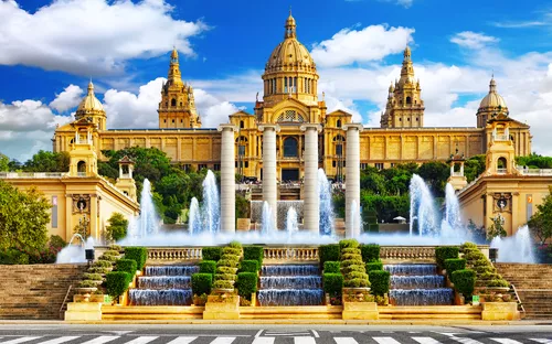 Historisches Gebäude mit Brunnen und Treppen vor blauem Himmel.
