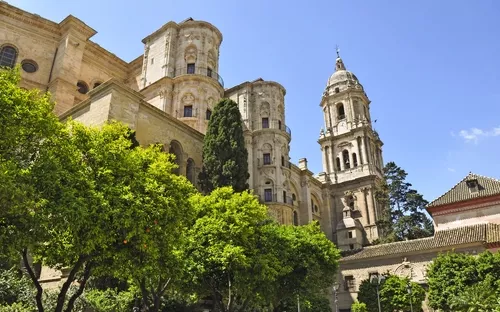 Kathedrale von Málaga in Spanien mit blauem Himmel und Bäumen im Vordergrund.