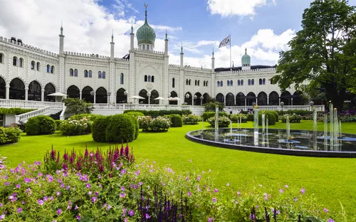 Gebäude mit Kuppeln und Türmen in einem blühenden Garten mit Springbrunnen.