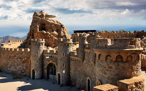 Steinburg mit Ruinen und Berglandschaft im Hintergrund.