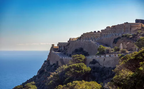 Große Gebäude auf Klippe mit Meerblick im Hintergrund.
