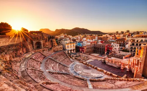 Römisches Amphitheater bei Sonnenuntergang mit Stadtansicht im Hintergrund