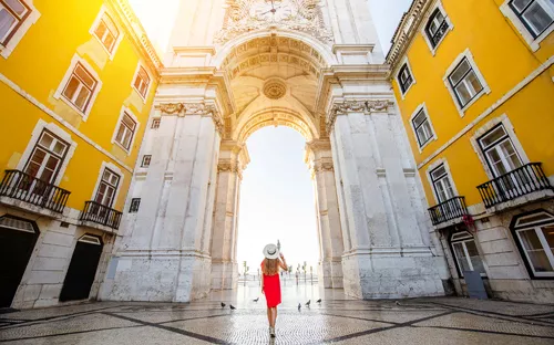 Frau in rotem Kleid vor dem Arco da Rua Augusta in Lissabon.