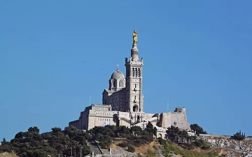 Historische Kirche auf einem Hügel vor blauem Himmel.