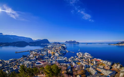 Luftaufnahme einer Küstenstadt mit Bergen und blauem Himmel.