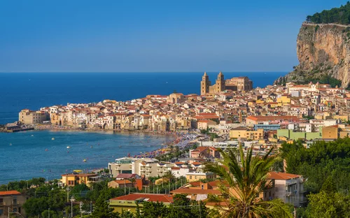 Küstenstadt mit historischen Gebäuden und blauem Meer im Hintergrund.