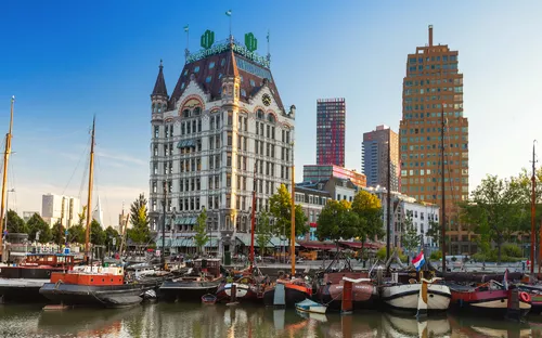 Hafen mit historischen Gebäuden und Booten bei blauem Himmel.