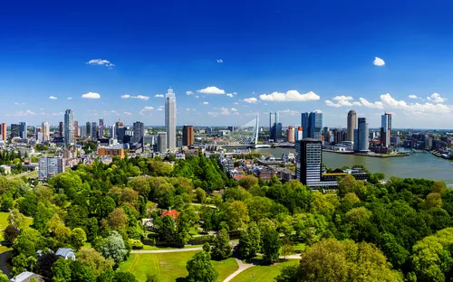Panorama einer Stadt mit modernen Hochhäusern und einem Fluss im Vordergrund.