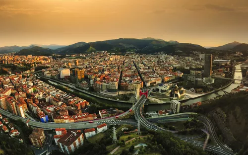 Luftaufnahme einer Stadt mit vielen Gebäuden und Straßen bei Sonnenuntergang.