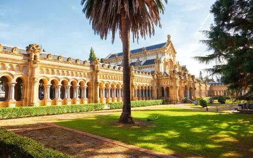 Historisches Gebäude mit Arkaden und Palmen im Vordergrund.