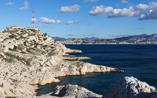 Küstenlandschaft mit Felsen und Blick auf das Meer unter blauem Himmel.