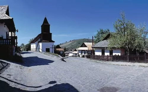 Historische Dorfstraße in Hollókő mit traditionellen Häusern und Kirche.