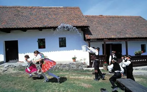 Traditionelles Osterbegießen mit Wasser vor einem ländlichen Gebäude.