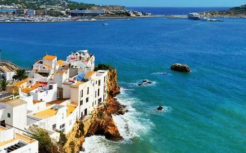 Küstenstadt mit weißen Häusern am blauen Meer an einem sonnigen Tag.