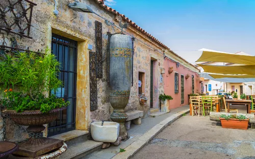 Malerische Gasse mit historischen Fassaden und Café-Tische im Freien.