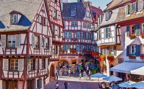 Fachwerkhäuser in einem belebten, sonnigen Platz in einer Altstadt.