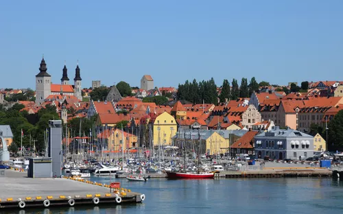 Hafen mit Segelbooten und Altstadt im Hintergrund bei klarem Himmel.