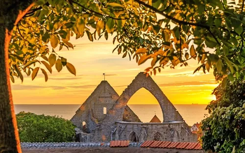 Ruinen einer Kirche bei Sonnenuntergang mit Meer im Hintergrund.